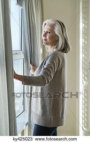 Stock Image - Woman standing by a window. Fotosearch
