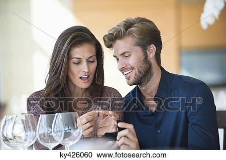 Stock Image - Man giving engagement ring to his girlfriend in a restaurant. Fotosearch