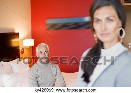 Stock Photo - Man looking at his wife in a hotel room. Fotosearch