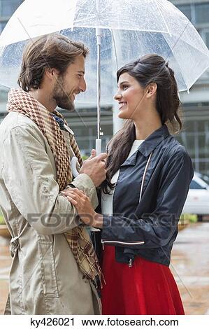 Stock Image - Smiling couple under an umbrella. Fotosearch