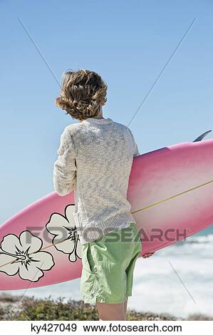 Stock Photo - Boy holding a surfboard on the beach. Fotosearch
