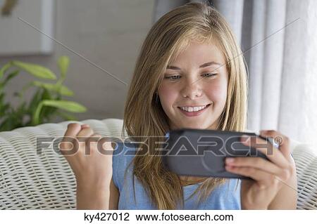 Close-up of a smiling girl playing video game View Large Photo Image Stock Image - Close-up of a smiling girl playing video game. Fotosearch
