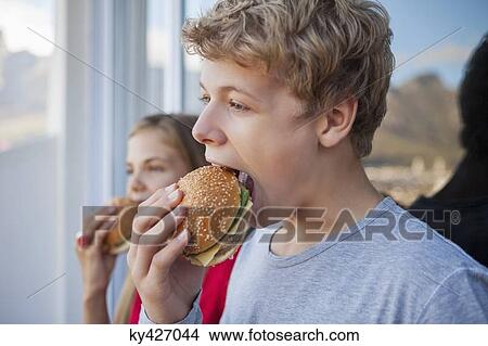 Close-up of two friends eating hamburger View Large Photo Image Picture - Close-up of two friends eating hamburger. Fotosearch