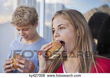 Stock Photo - Close-up of two friends eating hamburger. Fotosearch
