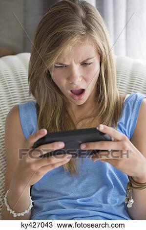 Girl looking shocked while playing video game View Large Photo Image Stock Image - Girl looking shocked while playing video game. Fotosearch
