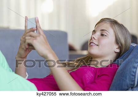 Girl lying on a bean bag and using a mobile phone View Large Photo Image Stock Photography - Girl lying on a bean bag and using a mobile phone. Fotosearch