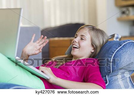 Girl video chatting on a laptop and smiling View Large Photo Image Stock Photograph - Girl video chatting on a laptop and smiling. Fotosearch