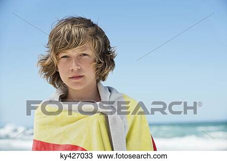 Stock Image - Portrait of a boy wrapped in a towel on the beach. Fotosearch