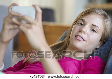 Portrait of a girl using a mobile phone and smiling View Large Photo Image Picture - Portrait of a girl using a mobile phone and smiling. Fotosearch