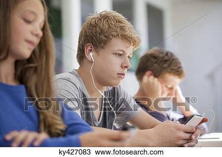 Stock Image - Students using electronic gadget in a classroom. Fotosearch