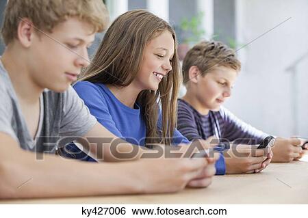 Stock Photograph - Students using electronic gadget in a classroom. Fotosearch