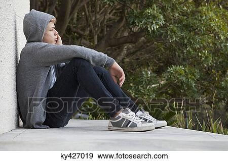 Stock Photo - Teenage boy leaning against a wall and thinking. Fotosearch