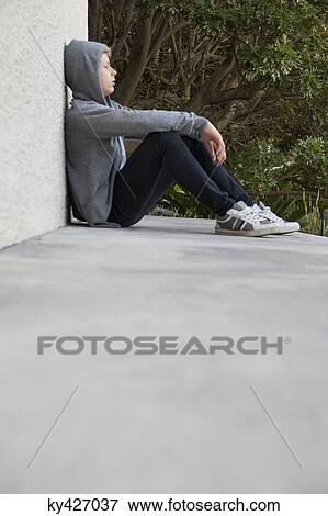 Stock Photo - Teenage boy leaning against a wall and thinking. Fotosearch
