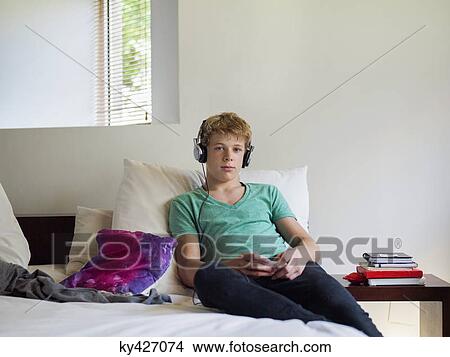 Picture - Teenage boy listening to music on a mobile phone. Fotosearch