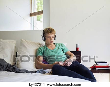 Teenage boy listening to music on a mobile phone View Large Photo Image Stock Image - Teenage boy listening to music on a mobile phone. Fotosearch