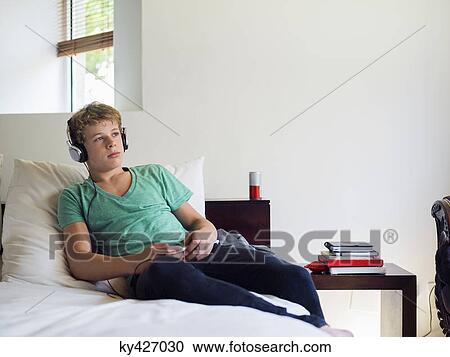 Teenage boy listening to music on a mobile phone View Large Photo Image Stock Image - Teenage boy listening to music on a mobile phone. Fotosearch