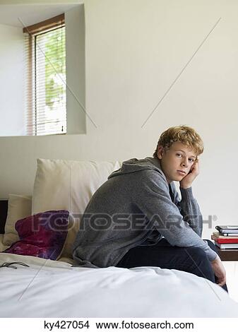 Teenage boy sitting on the bed and thinking View Large Photo Image Picture - Teenage boy sitting on the bed and thinking. Fotosearch