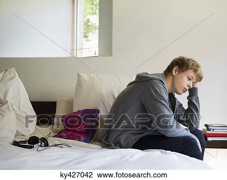 Teenage boy sitting on the bed and thinking View Large Photo Image Stock Image - Teenage boy sitting on the bed and thinking. Fotosearch