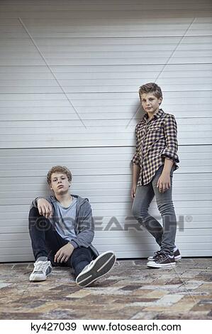 Two teenage boys leaning against a wall View Large Photo Image Stock Photo - Two teenage boys leaning against a wall. Fotosearch