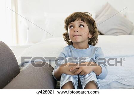 Boy sitting on the bed looking up View Large Photo Image Stock Image - Boy sitting on the bed looking up. Fotosearch