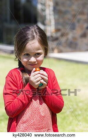 Close-up of a girl holding Easter eggs in a lawn View Large Photo Image Stock Image - Close-up of a girl holding Easter eggs in a lawn. Fotosearch