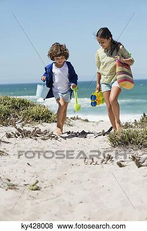 Stock Photo - Girl and a boy walking on the beach. Fotosearch
