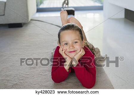 Stock Image - Girl lying on a carpet at home. Fotosearch