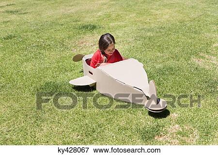 Stock Photo - Girl playing with a cardboard airplane in lawn. Fotosearch