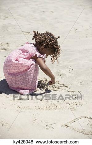 Girl playing with sand on the beach View Large Photo Image Stock Photo - Girl playing with sand on the beach. Fotosearch