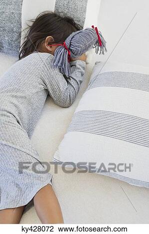 Stock Image - Girl sleeping on the bed with rag doll. Fotosearch