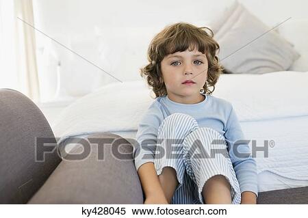 Stock Photography - Portrait of a boy sitting on the bed looking sad. Fotosearch
