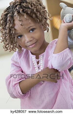 Stock Photo - Portrait of a girl holding a rag doll. Fotosearch