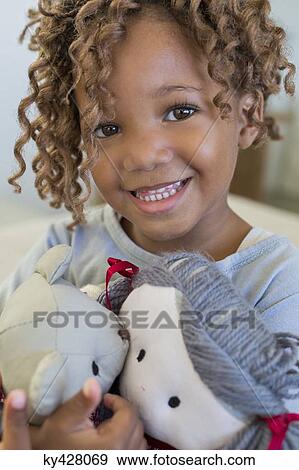 Stock Photo - Portrait of a girl holding dolls. Fotosearch