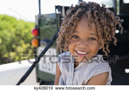 Stock Photo - Portrait of a girl sitting in a SUV and smiling. Fotosearch