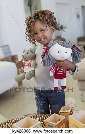 Stock Photograph - Portrait of a girl standing with dolls. Fotosearch