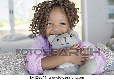 Stock Image - Portrait of a smiling girl holding a teddy bear. Fotosearch