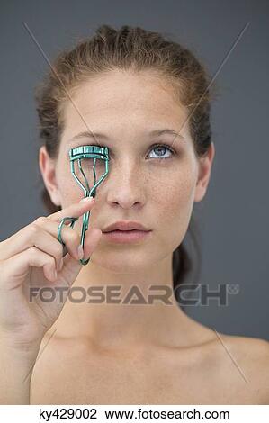 Close-up of a woman curling her eyelashes with eyelash curler View Large Photo Image Stock Image - Close-up of a woman curling her eyelashes with eyelash curler. Fotosearch