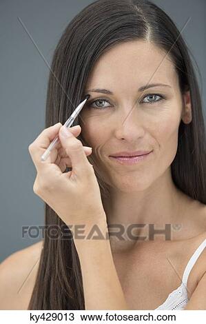 Portrait of a woman applying eyeliner View Large Photo Image Stock Image - Portrait of a woman applying eyeliner. Fotosearch