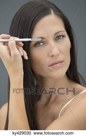 Stock Image - Portrait of a woman applying eyeliner. Fotosearch