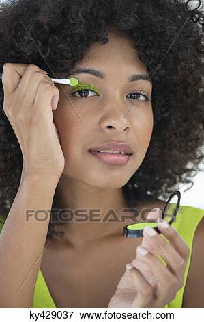 Stock Photo - Portrait of a woman applying eyeshadow. Fotosearch
