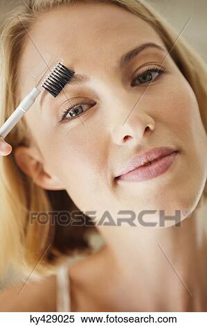 Portrait of a woman brushing her eyebrow View Large Photo Image Stock Photography - Portrait of a woman brushing her eyebrow. Fotosearch