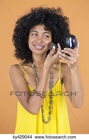 Smiling woman applying make-up on her face View Large Photo Image Picture - Smiling woman applying make-up on her face. Fotosearch