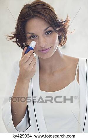 Woman applying anti wrinkle on her face View Large Photo Image Picture - Woman applying anti wrinkle on her face. Fotosearch