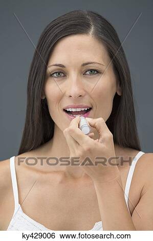 Woman applying lipstick View Large Photo Image Stock Photograph - Woman applying lipstick. Fotosearch