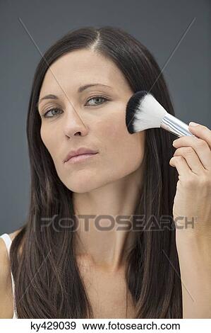 Stock Photo - Woman applying make-up on her face. Fotosearch