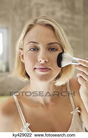Stock Image - Woman applying make-up with a brush. Fotosearch