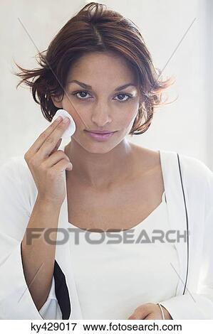 Stock Photo - Woman cleaning her face with a cotton pad. Fotosearch
