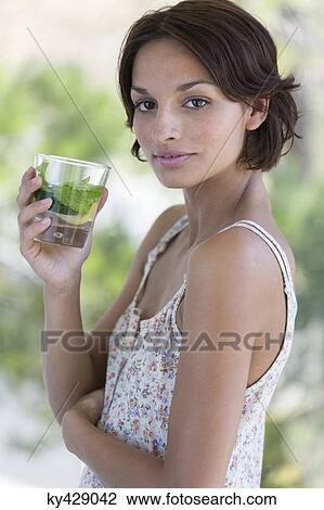Stock Image - Woman holding a cup of herbal tea. Fotosearch