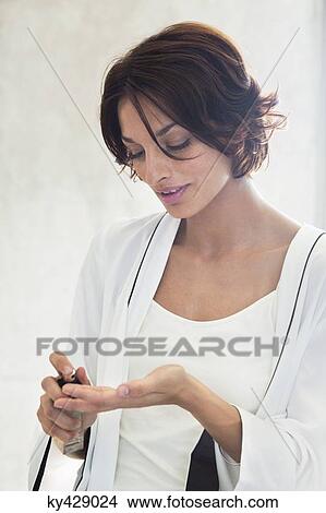 Woman spraying perfume onto her fingers View Large Photo Image Picture - Woman spraying perfume onto her fingers. Fotosearch