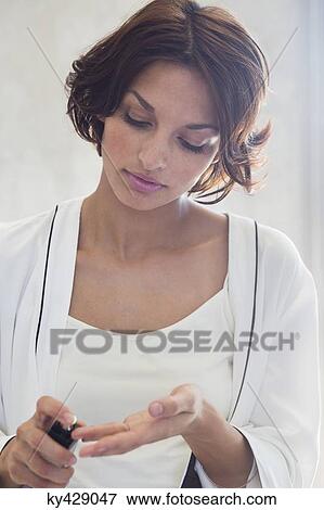 Stock Photo - Woman spraying perfume onto her fingers. Fotosearch